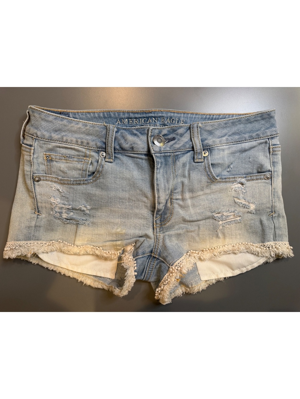 American Eagle distressed denim "Shortie" shorts with crochet lace/fringe trim